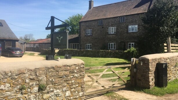 A stone wall, a wooden gate, and a building with a tiled roof.