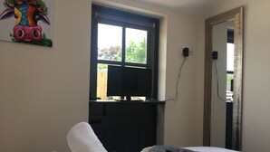 A hotel room with a bed, a window, a TV, and a mirror.