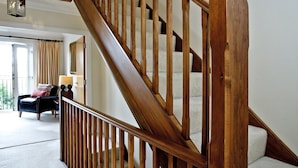 Eine hölzerne Treppe mit Geländer und abgerundeter Balustrade, die zu einer oberen Etage führt.