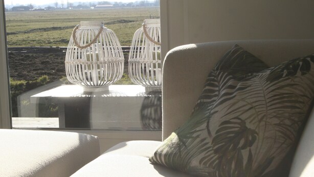A room with a sofa and two white lanterns by a window overlooking a field. - B&B depolderschuur is an independent home (Tienhoven)