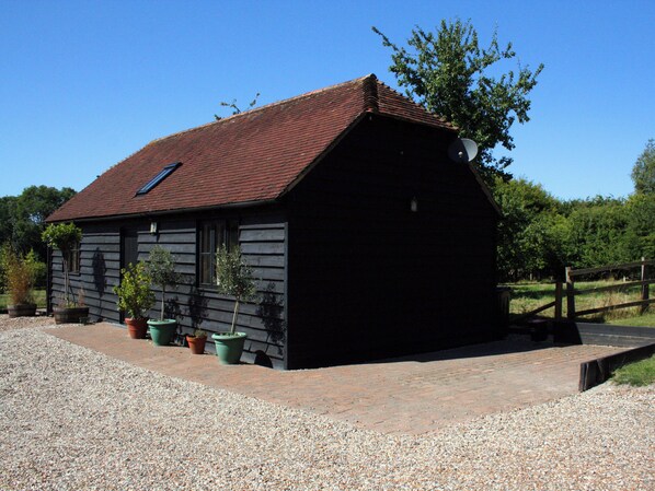 A single-story building with a sloped roof, a small window, and a door. - The Barn at Fishponds (Brook)