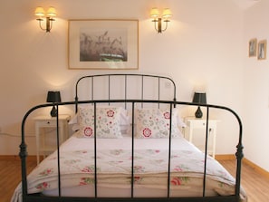 A bed with a floral bedspread, two bedside tables with lamps, and a framed picture on the wall. - The Barn at Fishponds (Brook)