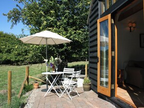 An outdoor patio with a table, chairs, and a large umbrella. - The Barn at Fishponds (Brook)