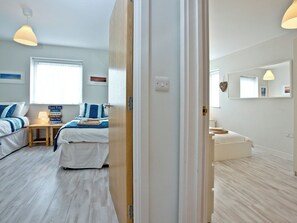 Quarto de hotel com cama, mesa de cabeceira, abajur e um aviso com as regras da praia.