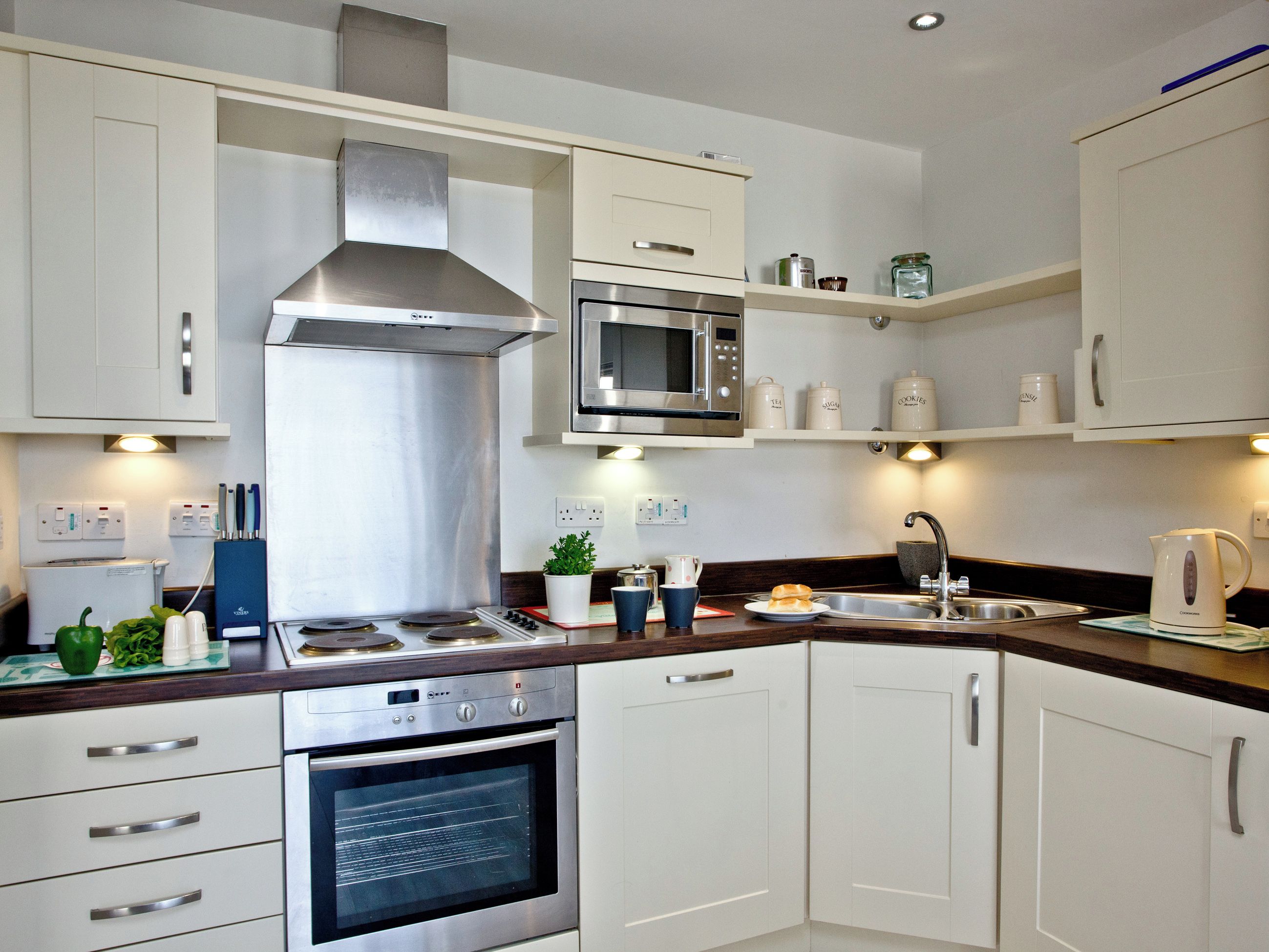A modern kitchen with stainless steel appliances, white cabinetry, and a built-in microwave.