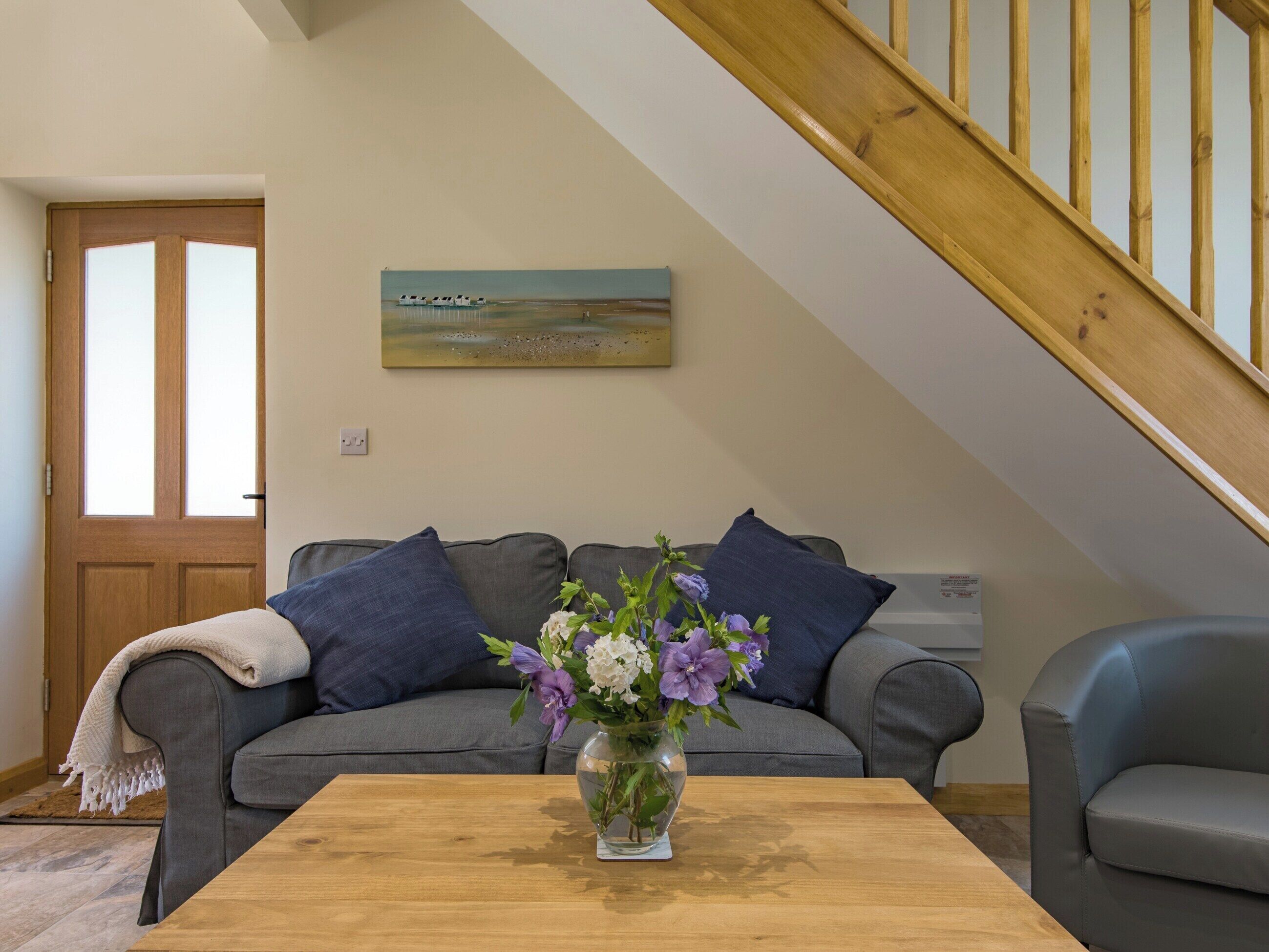 A living room with a grey sofa, a wooden coffee table, and a painting on the wall.