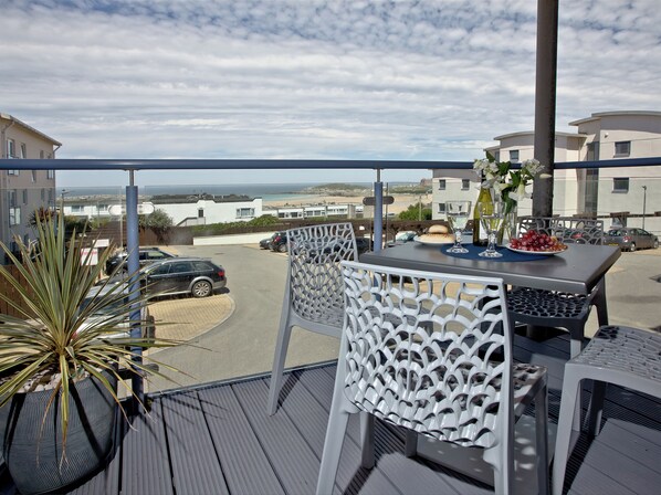 A balcony with a table, chairs, and a potted plant.