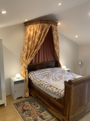 Ein Schlafzimmer mit einem hölzernen Bett, einem Nachttisch, einer Stehlampe und einem gemusterten Teppich.