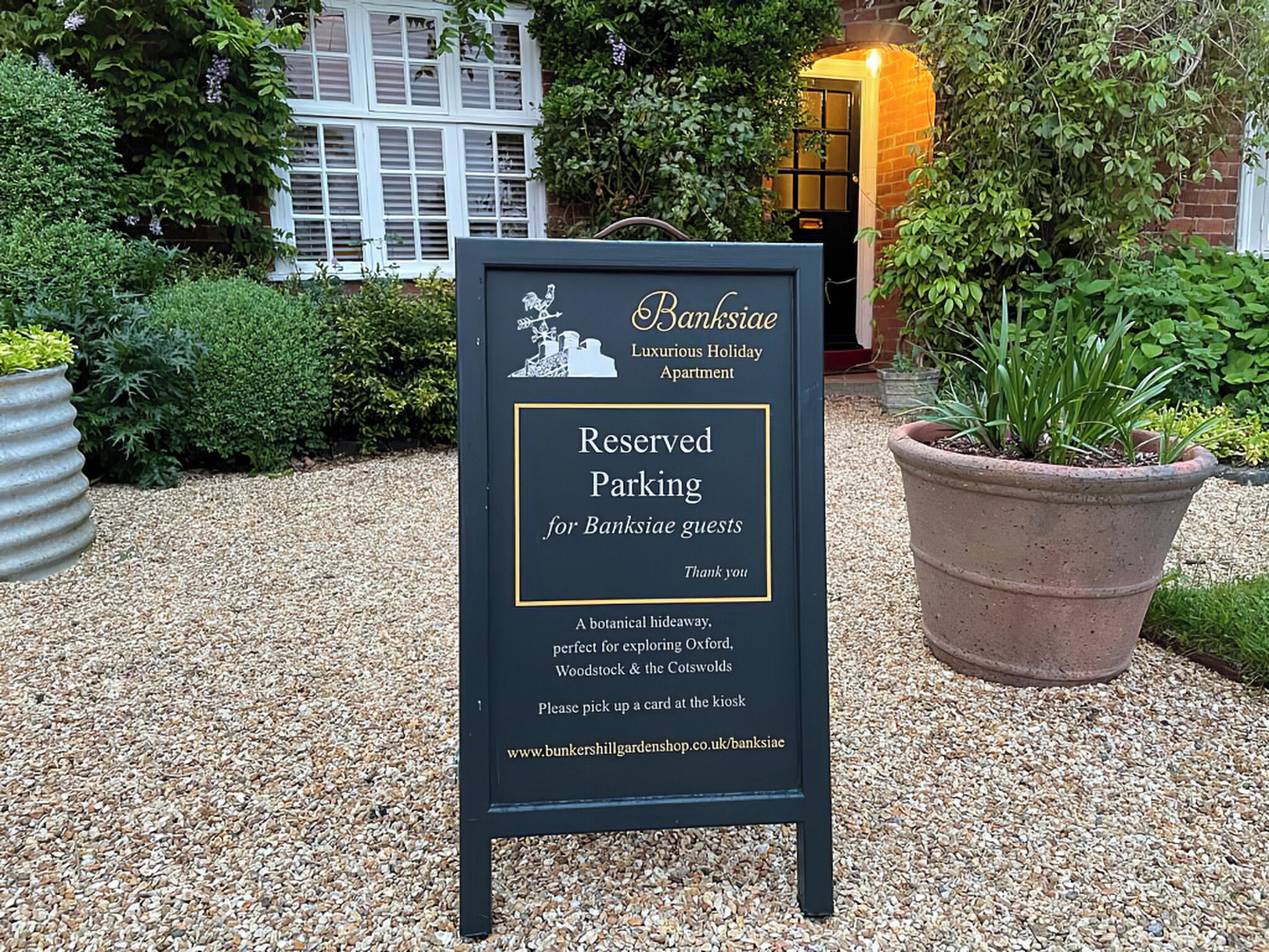 A sign for 'Banksiaceae Luxury Holiday Apartment' indicating reserved parking for guests.