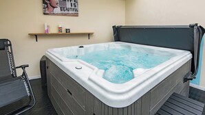 Een jacuzzi met een houten bankje, een plank met boeken en een fles, en een inspirerende poster aan de muur.