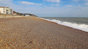 A pebble beach with a building complex in the background. - 1 bedroom accommodation in Sandgate (Sandgate)