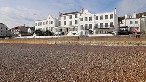 A coastal building with multiple stories, large windows, and a balcony. - 1 bedroom accommodation in Sandgate (Sandgate)