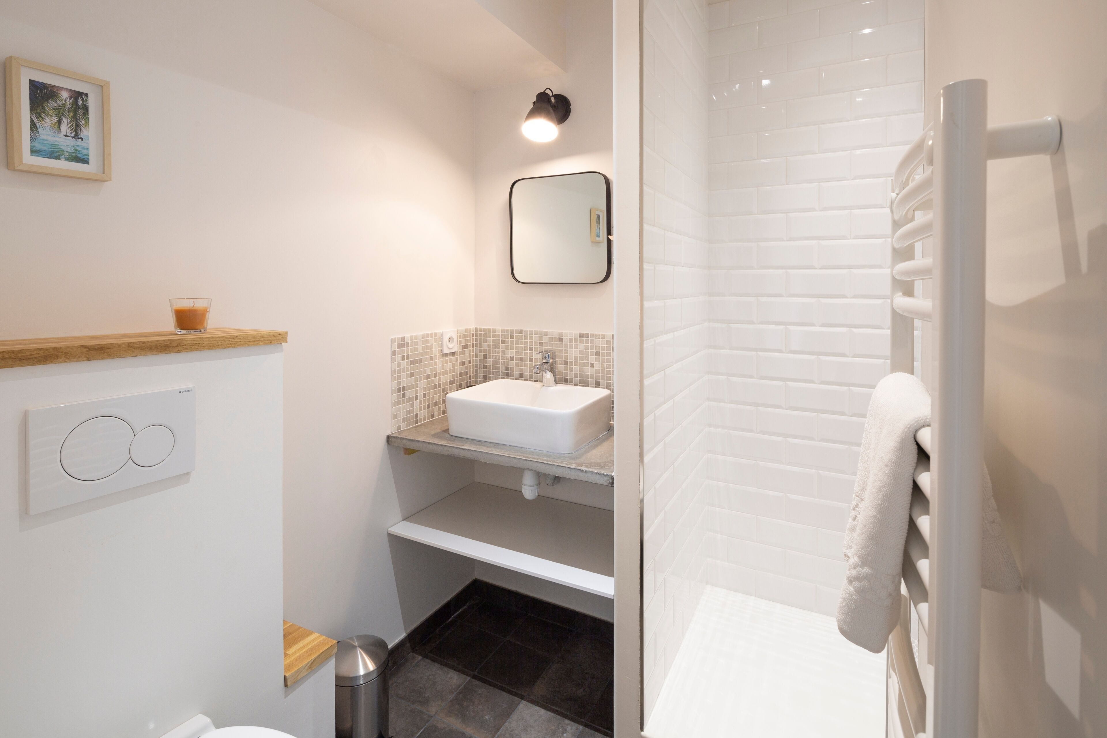 A modern bathroom with a white sink, a mirror, a towel rack, and a picture on the wall.