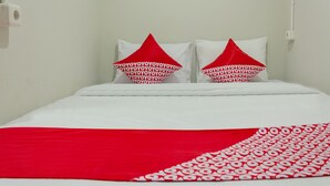 A bed with white bedding and red pillows with a pattern.