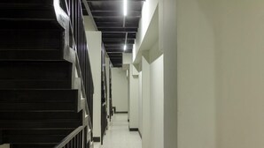 A corridor with a staircase on the left and a long hallway on the right.