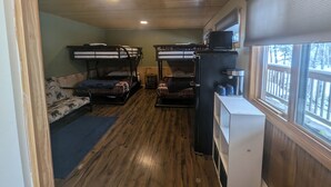 A cabin with bunk beds, a kitchenette, and a window with a view of trees.