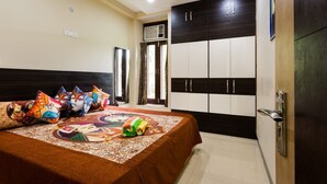 A bedroom with a bed, colorful pillows, a ceiling fan, and a wardrobe. - ACHLA PARADISE – LUXURY 2BHK APARTMENT (4 BEDS) (New Delhi)