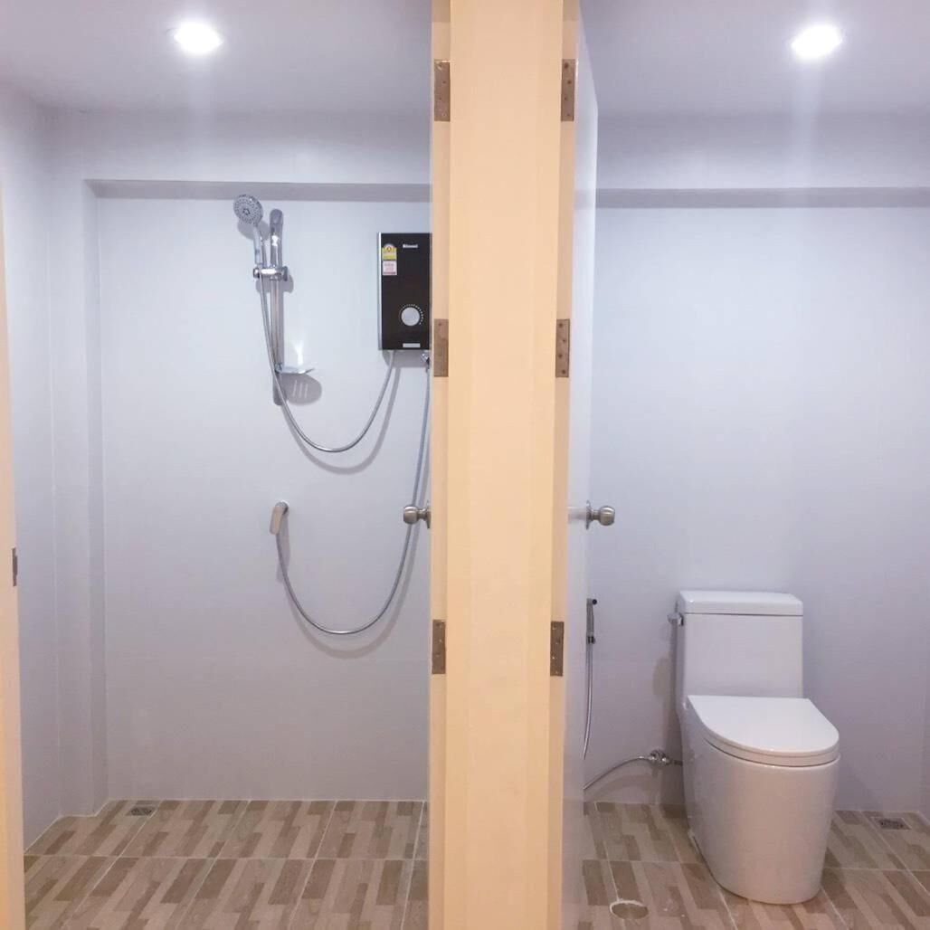 Un baño con ducha, inodoro y puerta de madera.