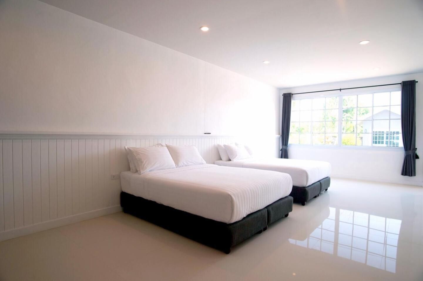 Un dormitorio amplio con dos camas, paredes blancas y ventanas grandes.