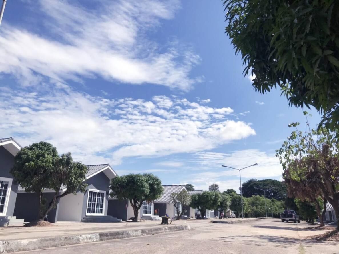 A residential street with houses, trees, and a clear sky.
