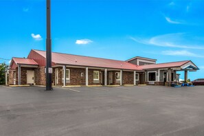 A two-story building with a red roof, a covered entrance, and a parking lot.