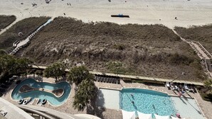 A beach resort with a swimming pool, a boardwalk, and a beach area.