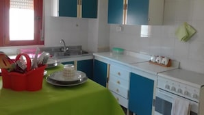 A kitchen with white cabinets, a sink, a stove, and a green tablecloth. - Vacation home !! (Trappeto)