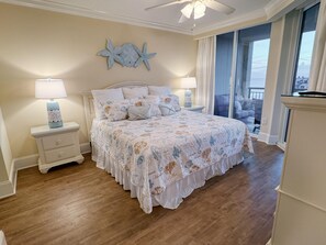 A bedroom with a bed, nightstands, a ceiling fan, and a view of the outdoors. - MVG 1116 4 Bedroom Ocean View (North Myrtle Beach)