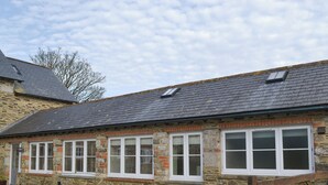A stone building with multiple windows and a sloped roof. - 2 bedroom accommodation in North Hill (North Hill)