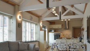 A spacious living area with a sofa, dining table, chairs, and a kitchen in the background. - 2 bedroom accommodation in North Hill (North Hill)