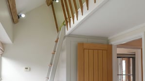 A staircase with wooden railings and a door with a vertical panel design. - 2 bedroom accommodation in North Hill (North Hill)