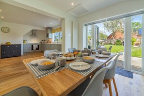 A modern kitchen with a dining area, large windows, and a view of the backyard.