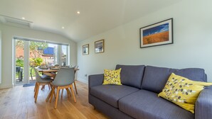 A modern living room with a grey sofa, yellow pillows, and a dining area with a table and chairs. - Stone Croft, Barney, Norfolk (Barney)