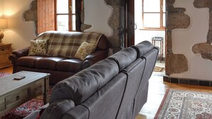 Un salon chaleureux avec un canapé en cuir marron, une table basse en bois et un tapis à motifs.