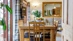 Un comedor con una mesa y sillas de madera, un cuenco de fruta y un sofá al fondo.