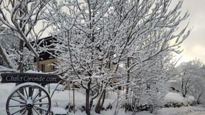 Een besneeuwde buitenruimte met een houten bord waarop staat: Chalet Gyronde.com.