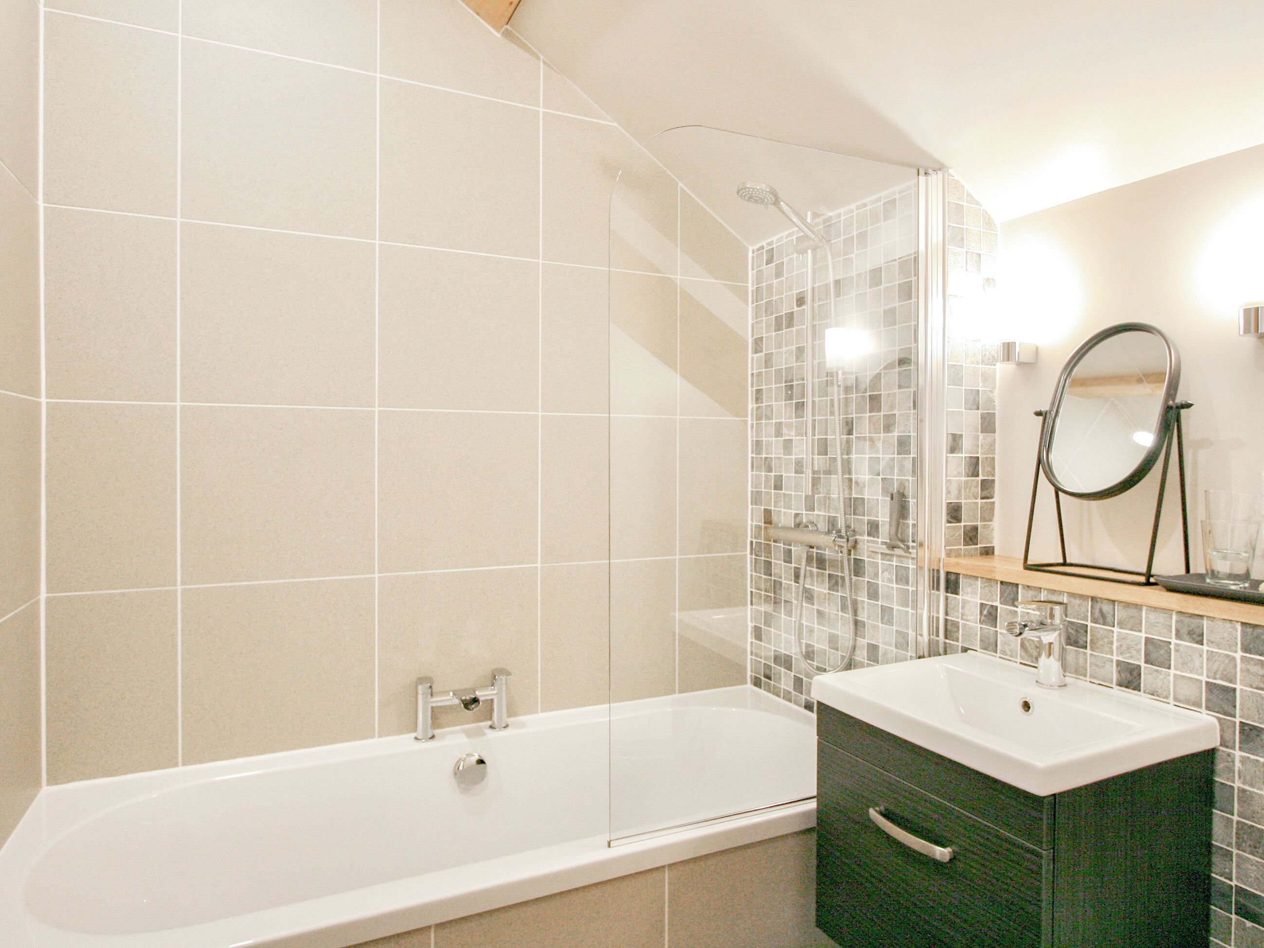 Ein Badezimmer mit Badewanne, Duschkabine und Waschtisch mit Spiegel.