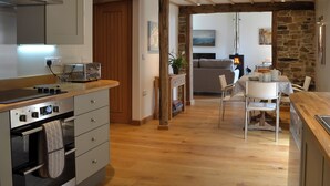 Una cocina moderna con vigas de madera, un comedor con pared de piedra y una chimenea.