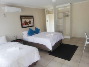 A hotel room with two beds, a black rug, a white chair, and a wardrobe with a mirror. - BTV Guesthouse (Mbombela)