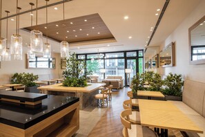 A modern restaurant interior with wooden tables, hanging pendant lights, and potted plants. - Hotel Vista Fukuoka Nakasu-Kawabata (Fukuoka)
