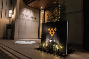 A hotel entrance with a prominent sign, a tiled wall, and a planter with plants. - Hotel Vista Fukuoka Nakasu-Kawabata (Fukuoka)