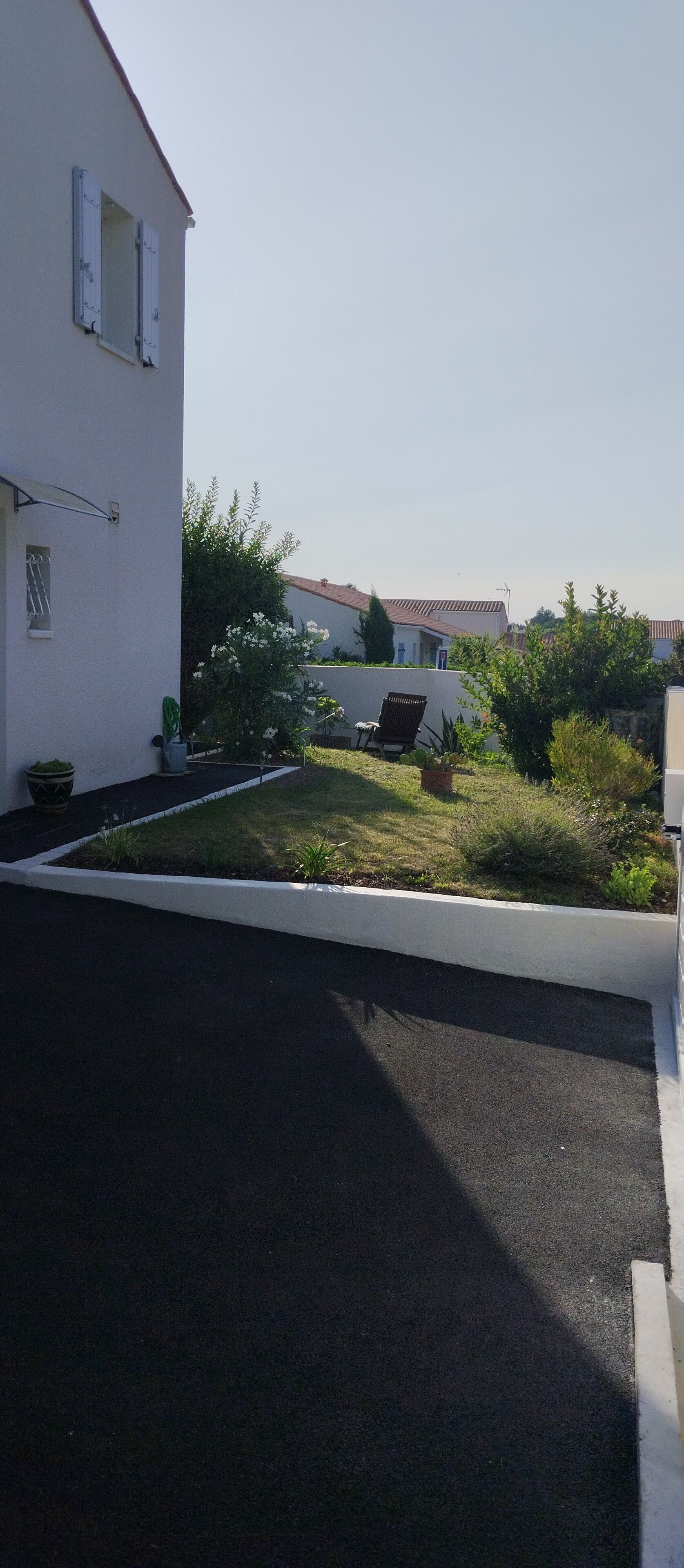 Un quartier résidentiel avec une allée pavée, une pelouse et un bâtiment blanc doté de volets.