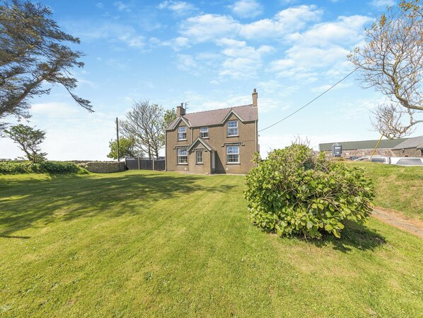 Une maison à deux étages, dotée d’une pelouse bien entretenue et d’un petit arbuste au premier plan.