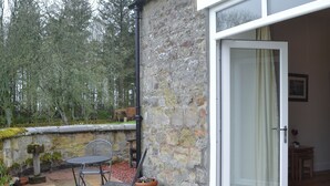 Un edificio de piedra con un patio, una mesa y sillas, y una puerta de acceso al interior.