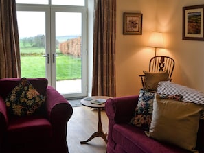 A room with a purple armchair, a wooden chair, a small table, and a view through a glass door. - 3 bedroom accommodation in Burradon, near Rothbury (Burradon, near Rothbury)