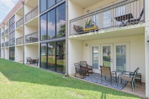 A multi-story building with balconies, outdoor seating, and a well-maintained lawn.