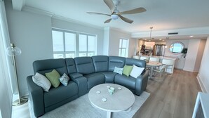 Een moderne woonkamer met een modulaire bank, een ronde salontafel en een plafondventilator.