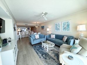 A modern living room with a blue sofa, a white coffee table, and a ceiling fan.