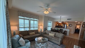 A living room with two sofas, a coffee table, and a dining area with a kitchen in the background.
