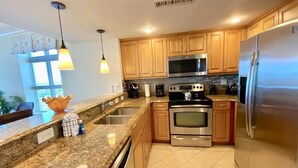 A kitchen with wooden cabinets, stainless steel appliances, granite countertops, and pendant lighting.